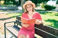 Young blonde woman on vacation reading book sitting on bench at the park Royalty Free Stock Photo