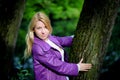 Young blonde woman in violet coat in park