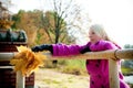 Young blonde woman in violet coat in park