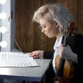 Young blonde woman violinist reads notes before a performance
