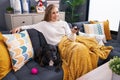 Young blonde woman watching movie sitting on sofa with dog at home Royalty Free Stock Photo