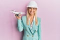 Young blonde woman wearing architect hardhat holding drone looking positive and happy standing and smiling with a confident smile Royalty Free Stock Photo
