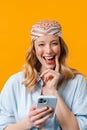 Young blonde woman wearing bandanna smiling and using cellphone