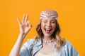 Young blonde woman wearing bandanna winking and showing ok sign