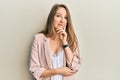 Young blonde woman wearing business jacket and glasses looking confident at the camera with smile with crossed arms and hand Royalty Free Stock Photo