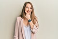 Young blonde woman wearing business jacket and glasses looking confident at the camera smiling with crossed arms and hand raised Royalty Free Stock Photo