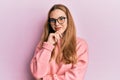 Young blonde woman wearing casual clothes and glasses smiling looking confident at the camera with crossed arms and hand on chin Royalty Free Stock Photo