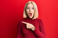 Young blonde woman wearing casual clothes surprised pointing with finger to the side, open mouth amazed expression Royalty Free Stock Photo