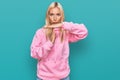 Young blonde woman wearing casual sweatshirt doing time out gesture with hands, frustrated and serious face Royalty Free Stock Photo
