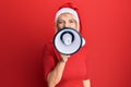 Young blonde woman wearing christmas hat screaming using megaphone over isolated red background Royalty Free Stock Photo