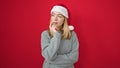 Young blonde woman wearing christmas hat thinking over isolated red background Royalty Free Stock Photo