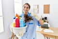 Young blonde woman wearing cleaner uniform holding cleaning products doing happy thumbs up gesture with hand Royalty Free Stock Photo