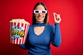 Young blonde woman wearing 3d glasses and eating pack of popcorn watching a movie on cinema with a happy and cool smile on face Royalty Free Stock Photo