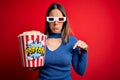 Young blonde woman wearing 3d glasses and eating pack of popcorn watching a movie on cinema Pointing down looking sad and upset, Royalty Free Stock Photo