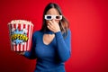 Young blonde woman wearing 3d glasses and eating pack of popcorn watching a movie on cinema smelling something stinky and