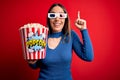 Young blonde woman wearing 3d glasses and eating pack of popcorn watching a movie on cinema smiling amazed and surprised and Royalty Free Stock Photo