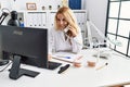 Young blonde woman wearing dentist uniform speaking on the phone at dental clinic