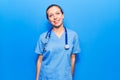Young blonde woman wearing doctor uniform and stethoscope looking positive and happy standing and smiling with a confident smile Royalty Free Stock Photo