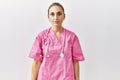 Young blonde woman wearing pink nurse uniform over isolated background with serious expression on face Royalty Free Stock Photo