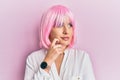 Young blonde woman wearing pink wig serious face thinking about question with hand on chin, thoughtful about confusing idea Royalty Free Stock Photo