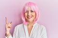 Young blonde woman wearing pink wig smiling happy pointing with hand and finger to the side Royalty Free Stock Photo