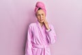 Young blonde woman wearing shower towel cap and bathrobe touching mouth with hand with painful expression because of toothache or Royalty Free Stock Photo