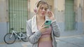 Young blonde woman wearing sportswear listening to music at street Royalty Free Stock Photo