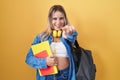 Young blonde woman wearing student backpack and holding books pointing to you and the camera with fingers, smiling positive and Royalty Free Stock Photo