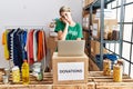 Young blonde woman wearing volunteer t shirt at donations stand thinking looking tired and bored with depression problems with