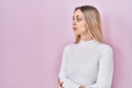Young blonde woman wearing white sweater over pink background looking to side, relax profile pose with natural face with confident Royalty Free Stock Photo