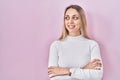 Young blonde woman wearing white sweater over pink background smiling looking to the side and staring away thinking Royalty Free Stock Photo