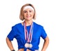 Young blonde woman wearing winner medals happy face smiling with crossed arms looking at the camera