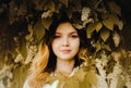 An young blonde woman with white bird cherry blossom flowers in her hair standing amidst the foliage of a blooming tree. Nature Royalty Free Stock Photo