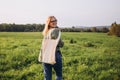 Young blonde woman with white cotton bag in her hands on nature background. Empty reusable canvas tote bag mockup for