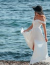 Young blonde woman in a white dress and black hat by the sea Royalty Free Stock Photo