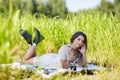 Young blonde woman in white dress lies on a picnic sheet in tall grass Royalty Free Stock Photo