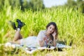 Young blonde woman in white dress lies on a picnic sheet in tall grass Royalty Free Stock Photo