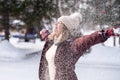 Young blonde woman in winter park having fun with snow falling in hands Royalty Free Stock Photo