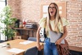 Young blonde woman working at the office holding bike helmet and laptop angry and mad screaming frustrated and furious, shouting Royalty Free Stock Photo