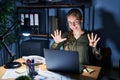 Young blonde woman working at the office at night showing and pointing up with fingers number nine while smiling confident and