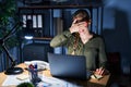 Young blonde woman working at the office at night smiling and laughing with hand on face covering eyes for surprise Royalty Free Stock Photo