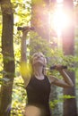 Young blonde woman working out with dumbbells outside in forested area Royalty Free Stock Photo