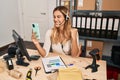 Young blonde woman working at small business ecommerce using headset screaming proud, celebrating victory and success very excited Royalty Free Stock Photo