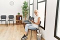 Young blonde woman writing on clipboard sitting on chair at waiting room Royalty Free Stock Photo