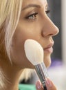 A young blonde 25-30 years old puts makeup on her face, close-up, selective focus. Royalty Free Stock Photo