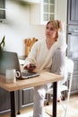 Young blondy woman freelancer at home communicates on smartphone