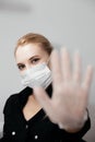 Young blong woman in white medical mask and transparent gloves showing STOP sign with hand. Royalty Free Stock Photo