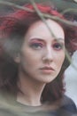 Young blue eyes woman portrait through the tree branch outdoor natural light closeup cold day