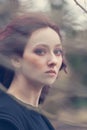 Young blue eyes woman portrait through the tree branch outdoor natural light closeup wind blows