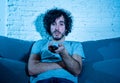 Portrait of bored sleepless young man sitting on the couch watching TV at night